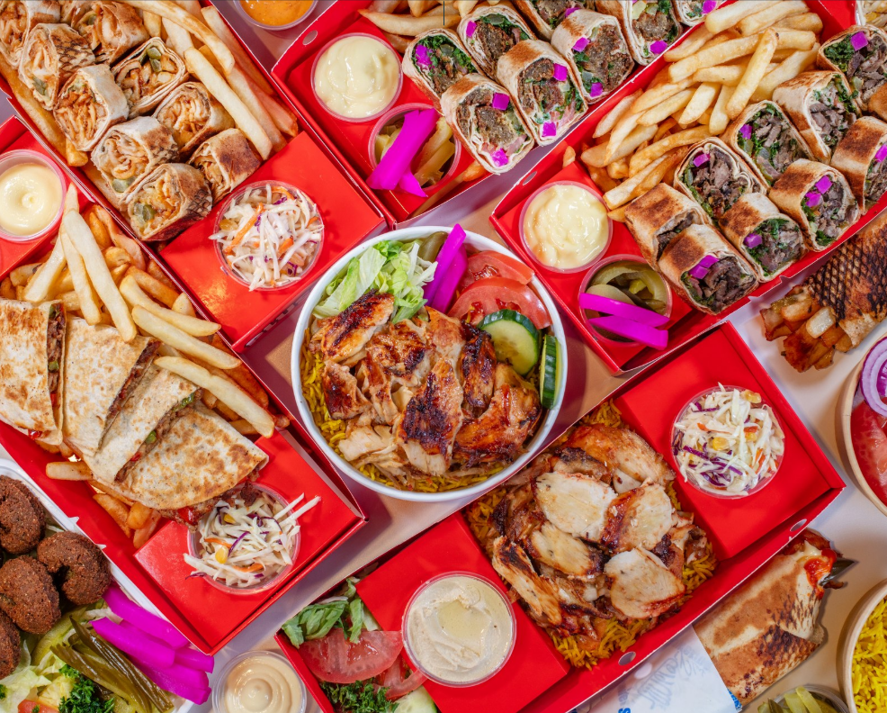 Overhead Shawerma Plus catering spread with Saj rolls, grilled chicken, rice, fries, salads and sauces